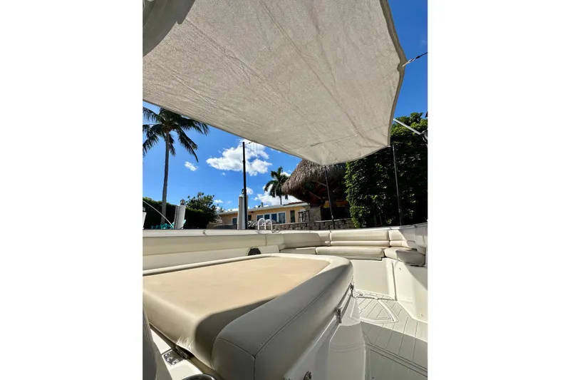 Slide: The Image of 2020 Boston Whaler 330 Outrage boat interior with sunshade, palm trees, and clear sky. - 26