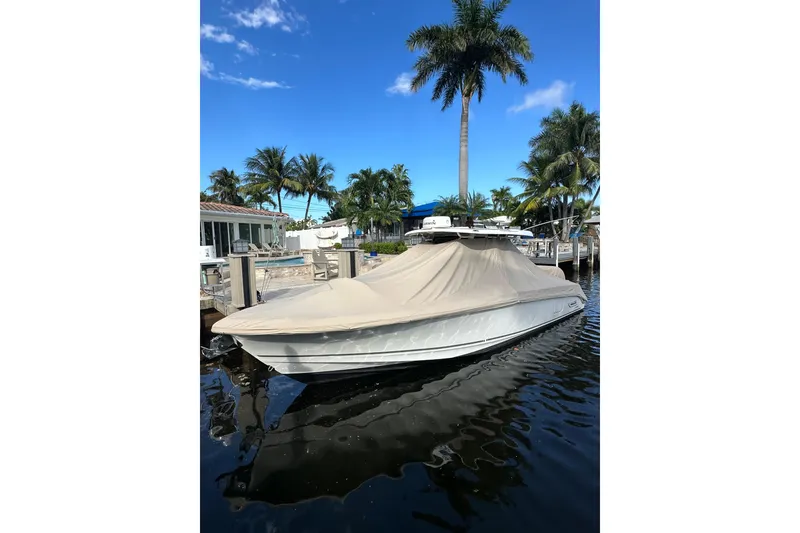 Slide: The Image of 2020 Boston Whaler 330 Outrage boat covered at dock, surrounded by palm trees. - 3