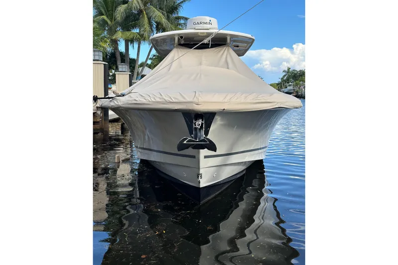 Slide: The Image of 2020 Boston Whaler 330 Outrage boat docked, covered, with palm trees in the background. - 4