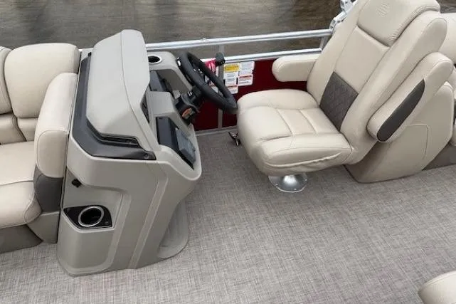 Slide: The Image of 2025 Sun Tracker Party Barge 24 DLX interior with beige seating and steering console. - 15
