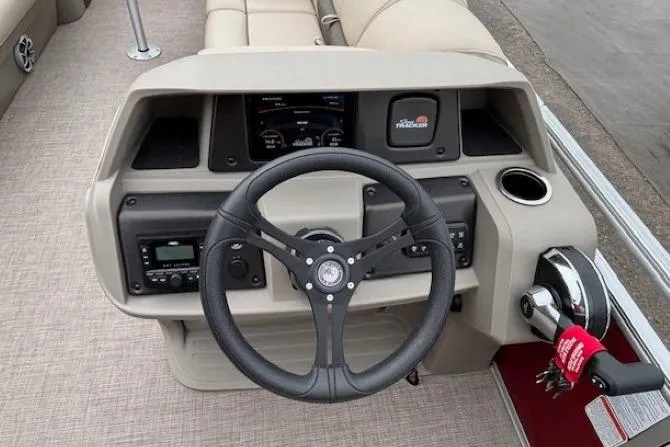 Slide: The Image of 2025 Sun Tracker Party Barge 24 DLX dashboard with steering wheel and controls. - 16