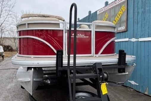 Slide: The Image of 2025 Sun Tracker Party Barge 24 DLX pontoon boat with red exterior, parked on a trailer. - 2