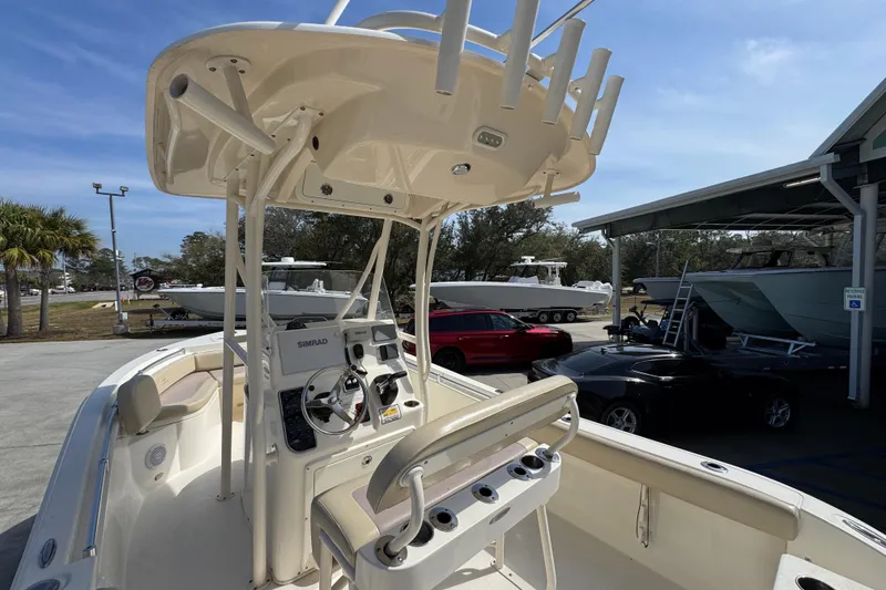 Slide: The Image of 2017 Cobia 220 Center Console boat with T-top and Simrad electronics in a marina setting. - 35