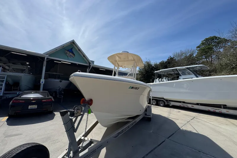 Slide: The Image of 2017 Cobia 220 Center Console boat on trailer, parked near other boats and a car. - 4