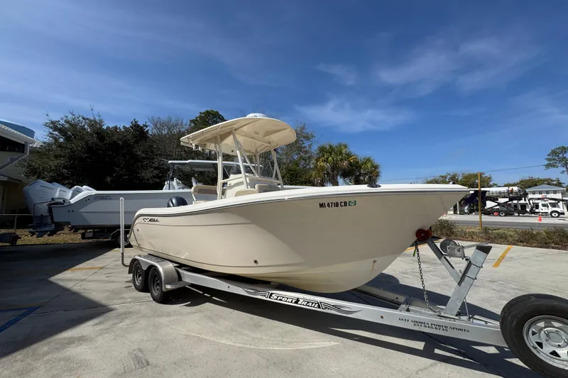 Slide: The Image of 2017 Cobia 220 Center Console boat on trailer, parked outdoors under clear blue sky. - 7