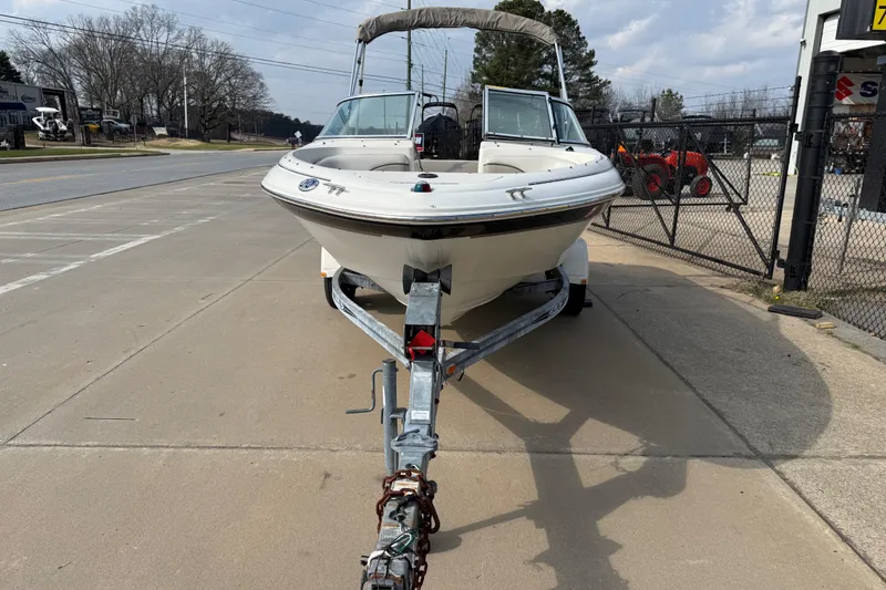 Slide: The Image of 2003 Sea Ray 185 Bow Rider on trailer, parked outdoors near a fence. - 2