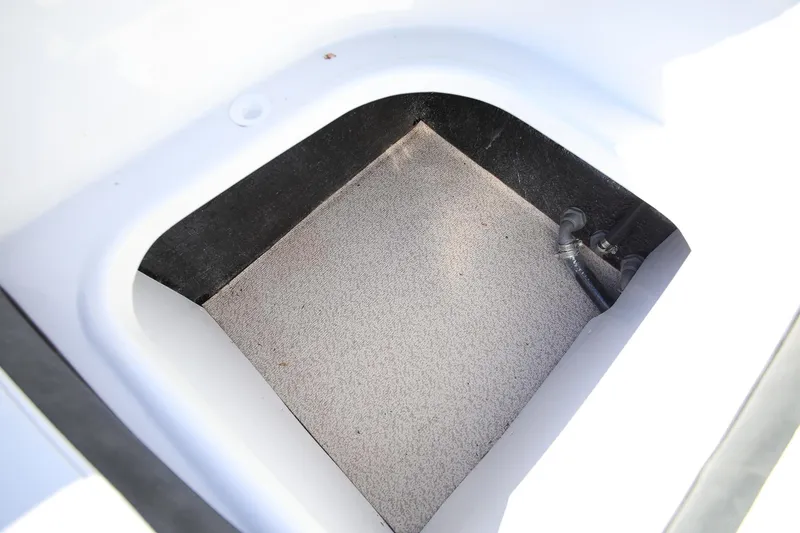 Slide: The Image of Storage compartment of 2025 Stingray 192 SC boat, featuring carpeted interior and visible piping. - 10