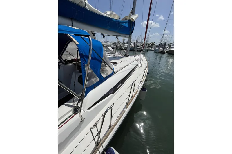 Slide: The Image of 2017 Jeanneau Sun Odyssey 419 sailboat docked in marina, featuring blue canopy and sleek design. - 17