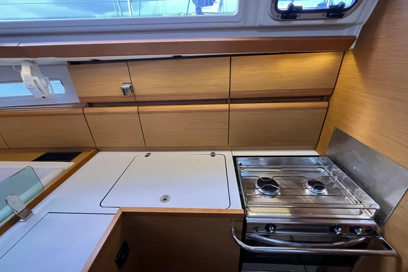Slide: The Image of 2017 Jeanneau Sun Odyssey 419 yacht kitchen with stove and wooden cabinetry. - 29