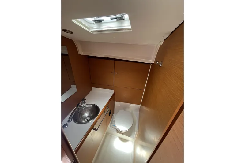 Slide: The Image of 2017 Jeanneau Sun Odyssey 419 yacht bathroom with sink, toilet, and wooden cabinetry. - 37
