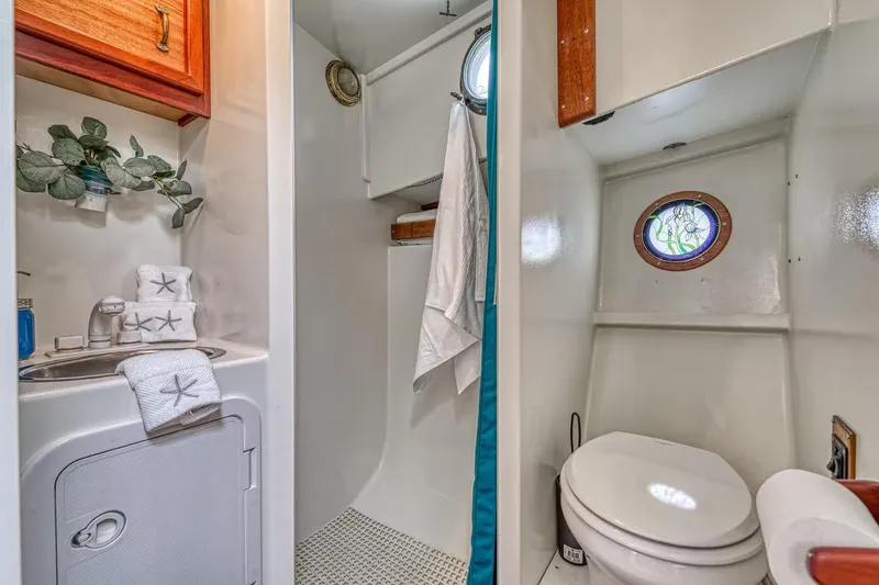 Slide: The Image of Compact 1996 Devlin 38 boat bathroom with sink, toilet, porthole, and nautical decor. - 10