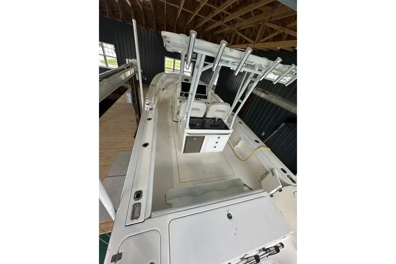 Slide: The Image of 2015 Edgewater 320CC boat interior with seating and storage, docked in a covered area. - 11