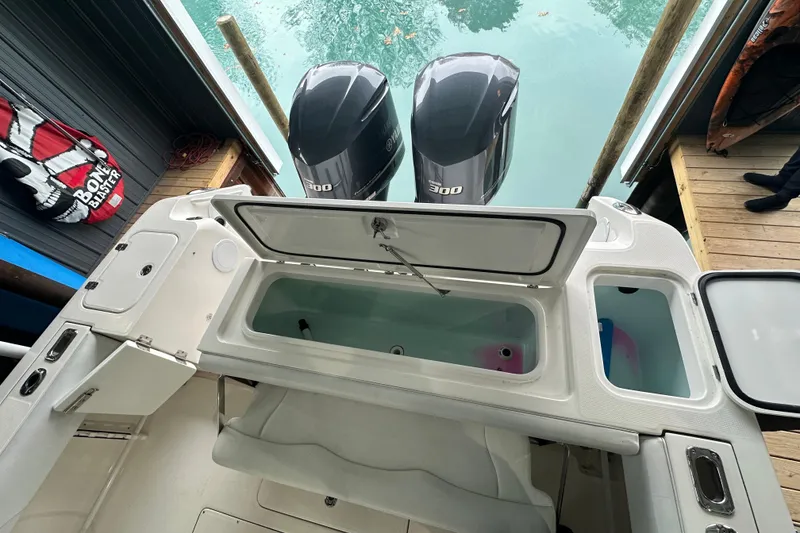 Slide: The Image of 2015 Edgewater 320CC boat with open storage compartments and dual outboard engines. - 12
