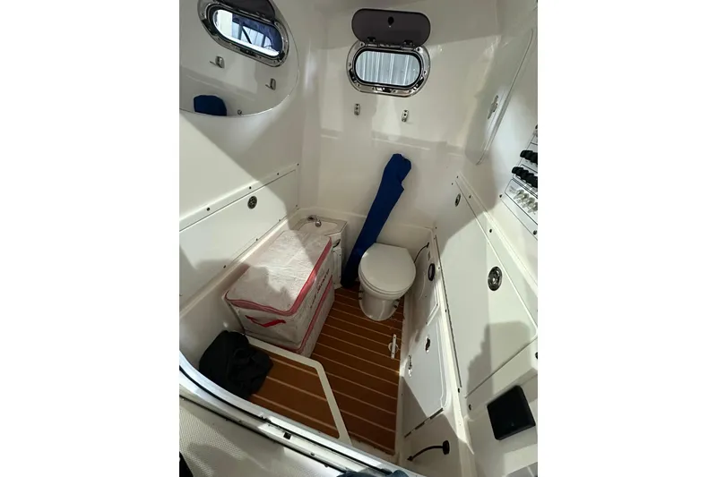 Slide: The Image of Interior of 2015 Edgewater 320CC boat featuring a compact marine toilet. - 13