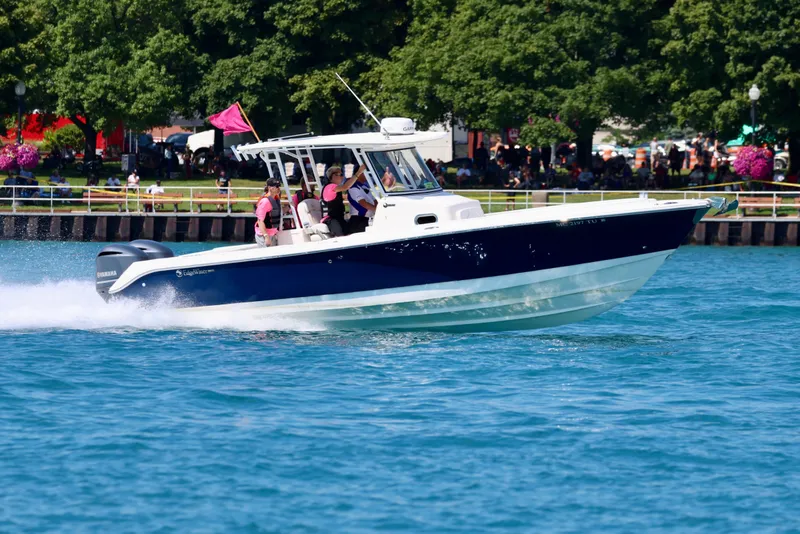 Slide: The Image of 2015 Edgewater 320CC boat cruising on a sunny day near a park shoreline. - 15
