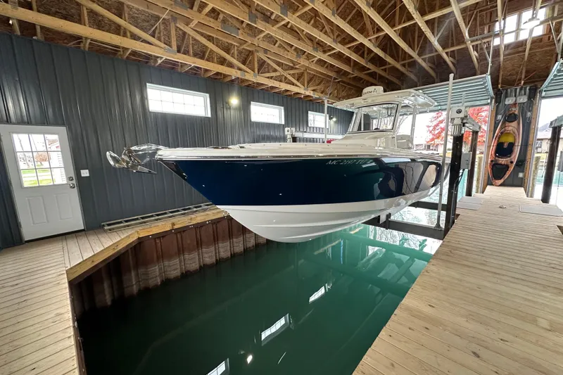 Slide: The Image of 2015 Edgewater 320CC boat in a boathouse, suspended above water. - 2
