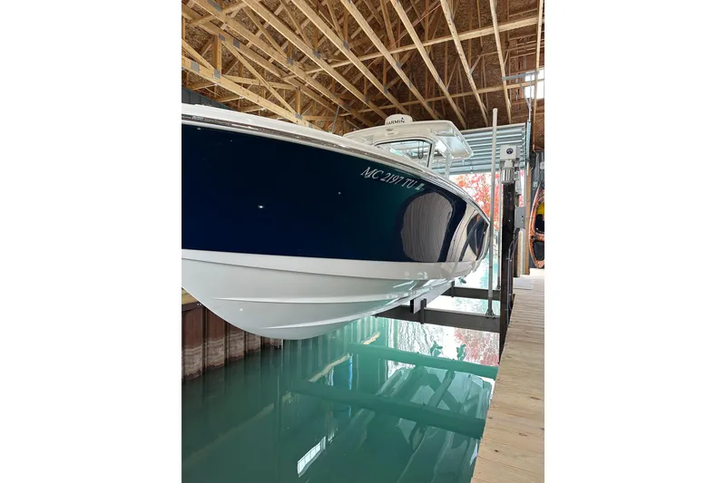 Slide: The Image of 2015 Edgewater 320CC boat in dock, blue hull, wooden ceiling, calm water reflection. - 3