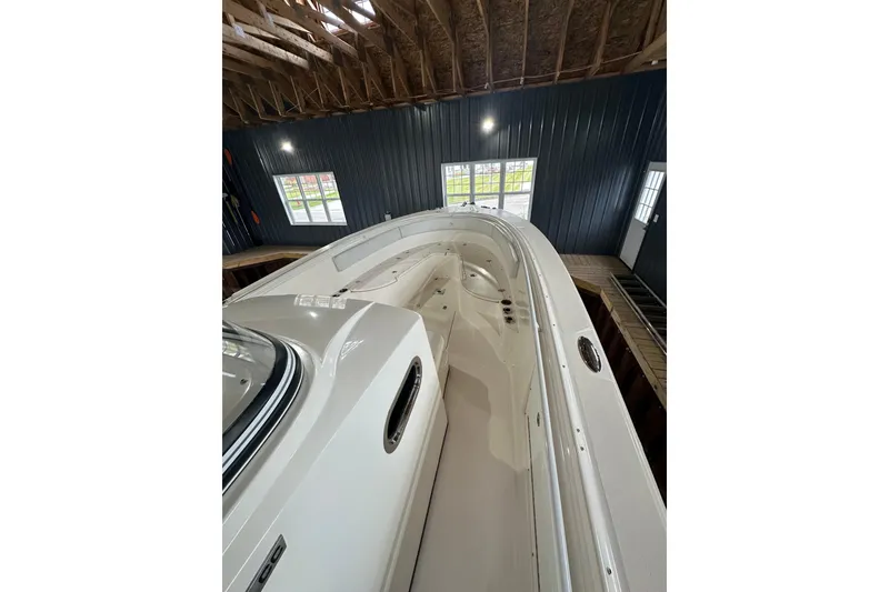 Slide: The Image of 2015 Edgewater 320CC boat in indoor storage, showcasing sleek design and spacious deck. - 7