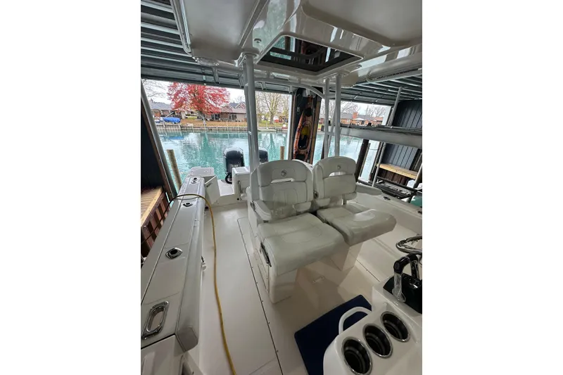 Slide: The Image of 2015 Edgewater 320CC boat interior with dual seats, docked by a serene lake. - 8