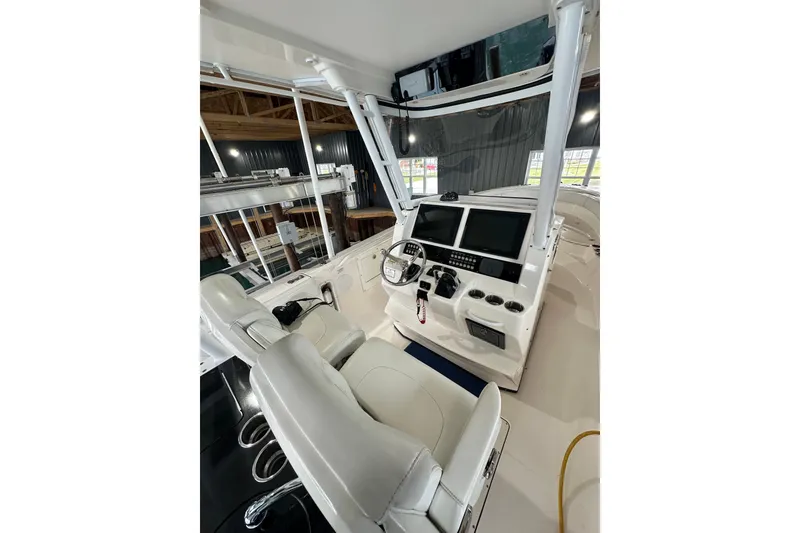 Slide: The Image of 2015 Edgewater 320CC boat cockpit with dual screens and white seating. - 9