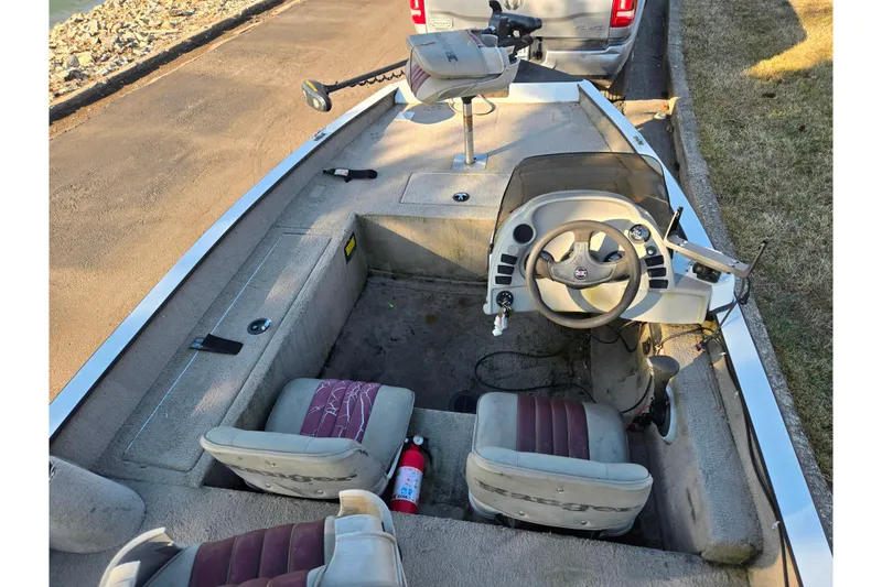 Slide: The Image of 2002 Ranger 116 Cherokee boat interior with steering wheel and seats, parked near a road. - 10
