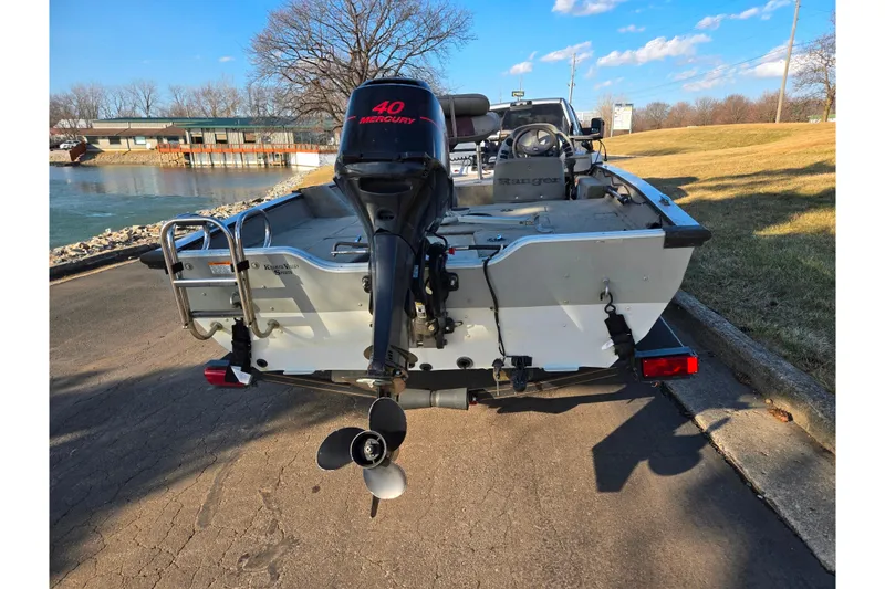 Slide: The Image of 2002 Ranger 116 Cherokee boat with 40 Mercury outboard motor, parked near a lake. - 2