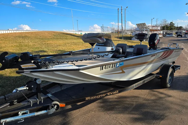 Slide: The Image of 2002 Ranger 116 Cherokee fishing boat on trailer, parked outdoors under blue sky. - 6