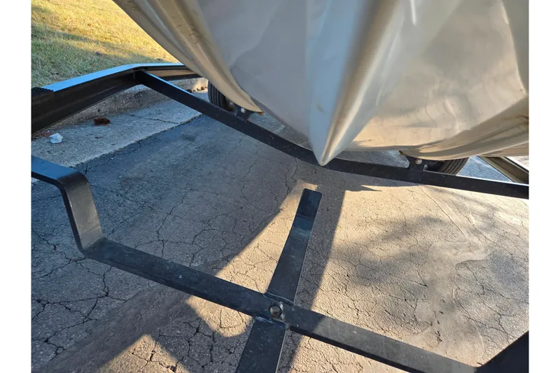 Slide: The Image of Trailer holding a 2002 Ranger 116 Cherokee boat on a cracked pavement. - 8