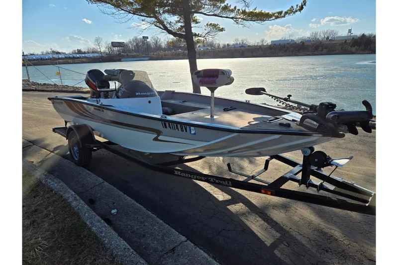 Slide: The Image of 2002 Ranger 116 Cherokee boat on trailer by a lake, under a clear sky. - 9