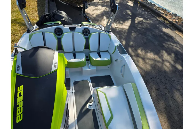 Slide: The Image of 2015 Scarab 165 H.O. Impulse boat interior with green and white seating, docked by the water. - 16