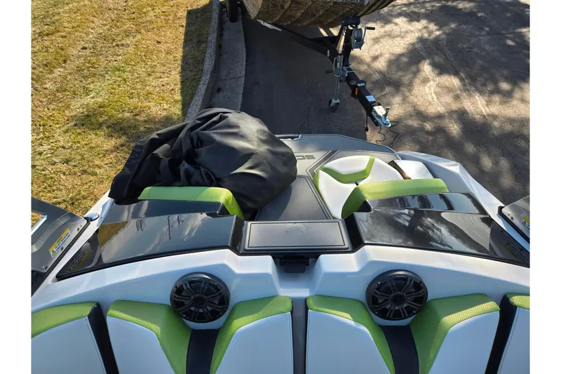Slide: The Image of 2015 Scarab 165 H.O. Impulse boat with green seats and speakers, parked on a trailer. - 18