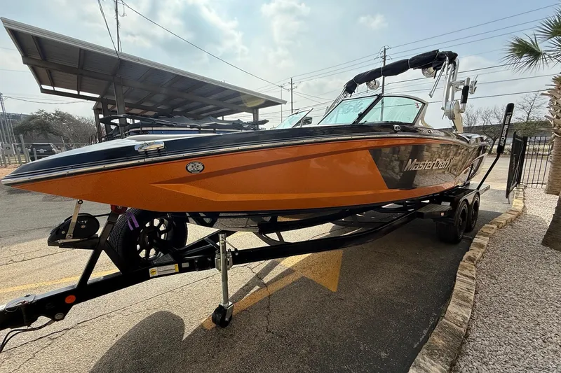 Slide: The Image of 2017 MasterCraft X46 boat on trailer, orange and black design, parked outdoors. - 3