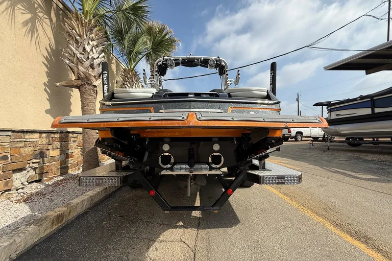 Slide: The Image of 2017 MasterCraft X46 boat rear view, parked outdoors with palm trees and clear sky. - 6