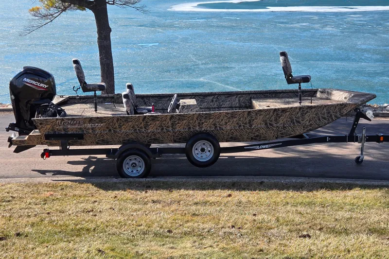 The Image of 2020 Lowe Roughneck 2070SC boat on trailer by a lake. - 0