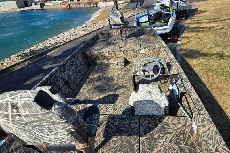Slide: The Image of 2020 Lowe Roughneck 2070SC boat with camouflage design, parked near a waterfront. - 11