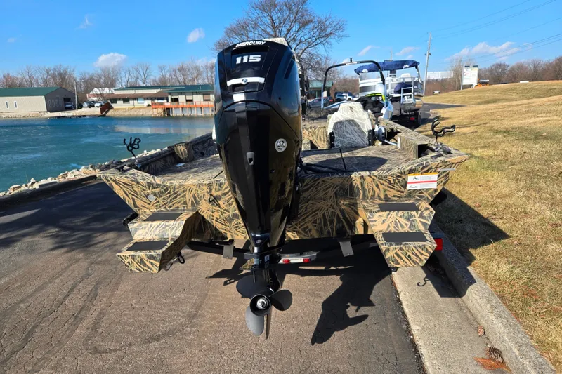 Slide: The Image of 2020 Lowe Roughneck 2070SC boat with camo design and Mercury 115 engine by a lake. - 2