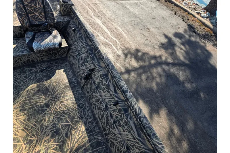 Slide: The Image of Camouflage interior of 2020 Lowe Roughneck 2070SC boat with shadowed pavement background. - 20