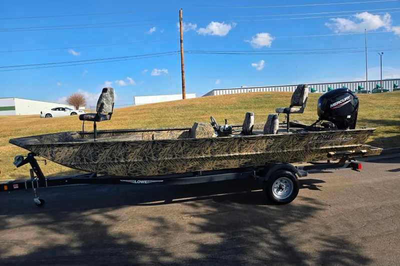 Slide: The Image of 2020 Lowe Roughneck 2070SC boat with camouflage design on a trailer, parked outdoors. - 5