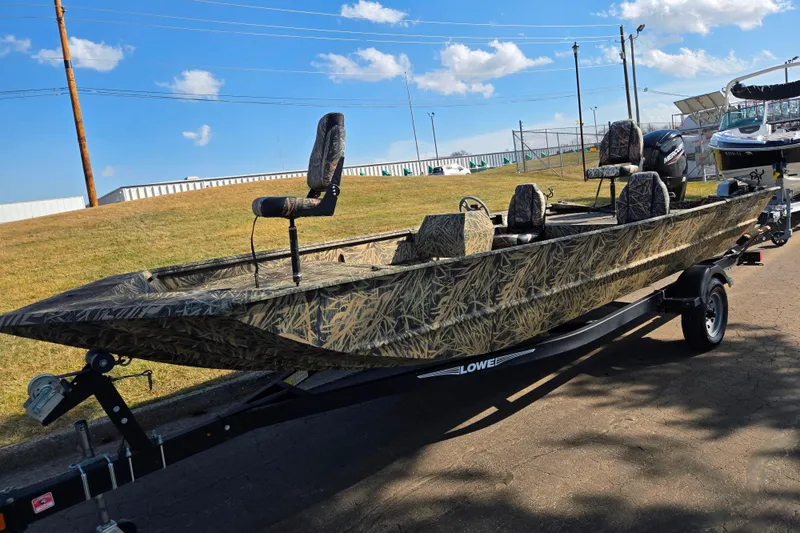 Slide: The Image of 2020 Lowe Roughneck 2070SC boat with camouflage design on a trailer, under a clear blue sky. - 6