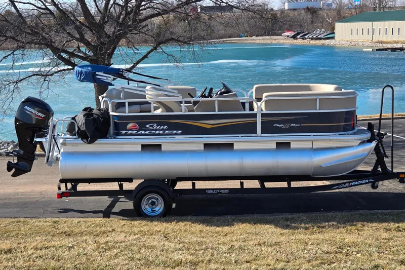 The Image of 2021 Sun Tracker Party Barge 18 DLX pontoon boat on trailer by a lake. - 0