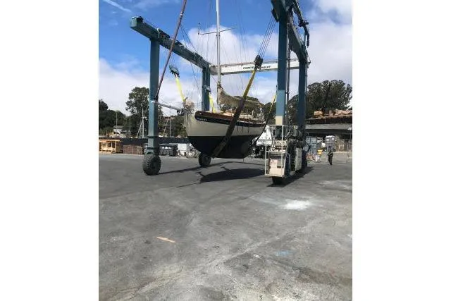 Slide: The Image of Bristol Channel Cutter 28 sailboat from 1997 being lifted by a crane in a shipyard. - 9