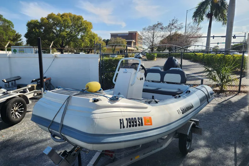 The Image of 2021 Highfield Sport 330 inflatable boat on trailer, parked outdoors near palm trees. - 0