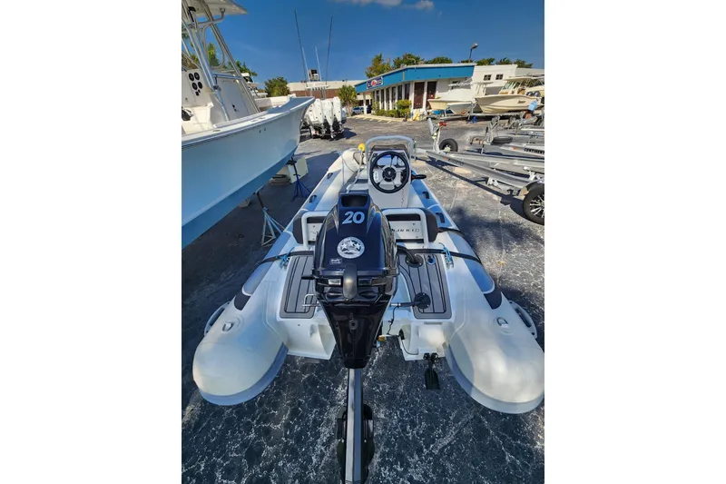 Slide: The Image of 2021 Highfield Sport 330 inflatable boat with outboard motor in a marina setting. - 4