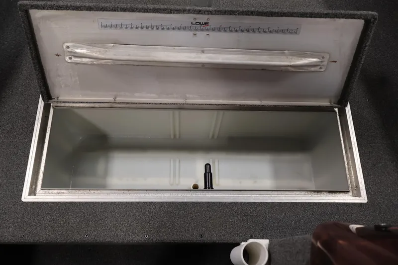 Slide: The Image of Open storage compartment in a 1990 Lowe 1620V boat, featuring a measuring ruler. - 18