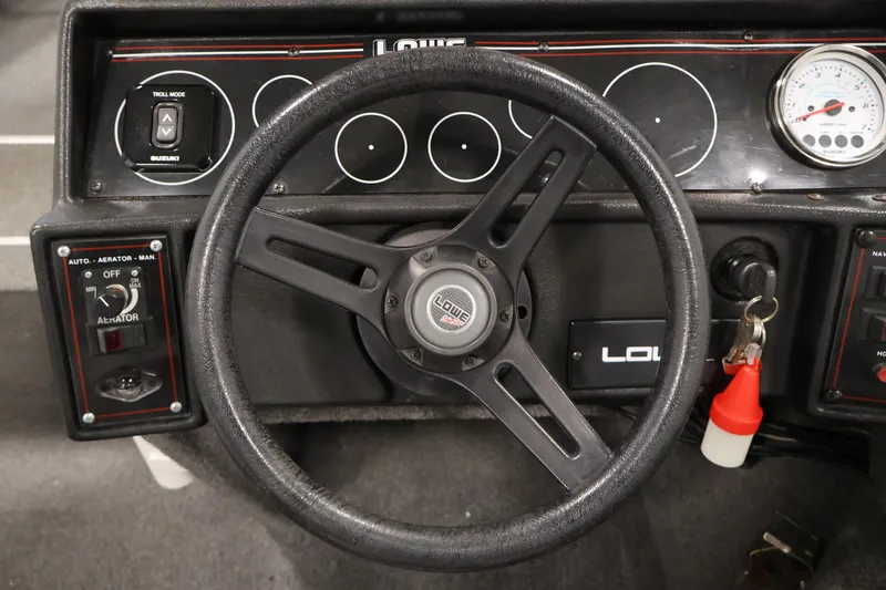 Slide: The Image of Steering wheel and dashboard of a 1990 Lowe 1620V boat with control panels. - 22
