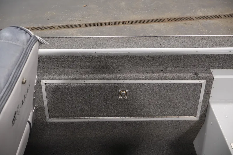 Slide: The Image of Interior of a 1990 Lowe 1620V boat, featuring carpeted storage compartment. - 33
