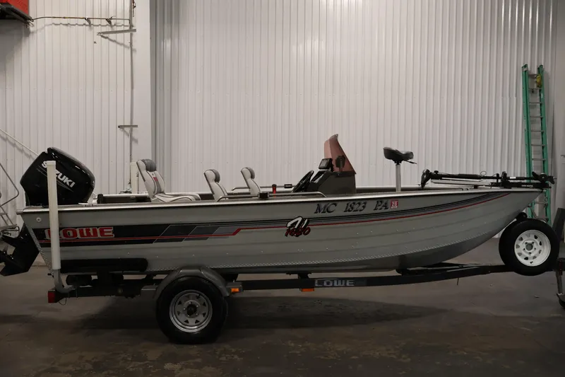 Slide: The Image of 1990 Lowe 1620V fishing boat on trailer in indoor storage. - 4