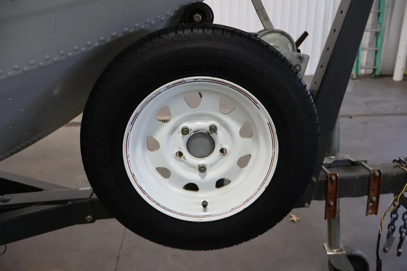 Slide: The Image of Trailer wheel of a 1990 Lowe 1620V boat, featuring a white rim and black tire. - 44