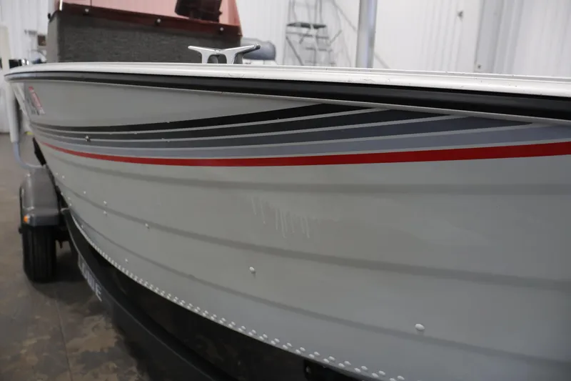 Slide: The Image of 1990 Lowe 1620V boat with sleek gray and red stripes on a trailer. - 48