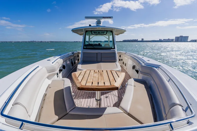 Slide: The Image of 2019 Boston Whaler 380 Outrage boat on open water, featuring spacious seating and wooden table. - 13